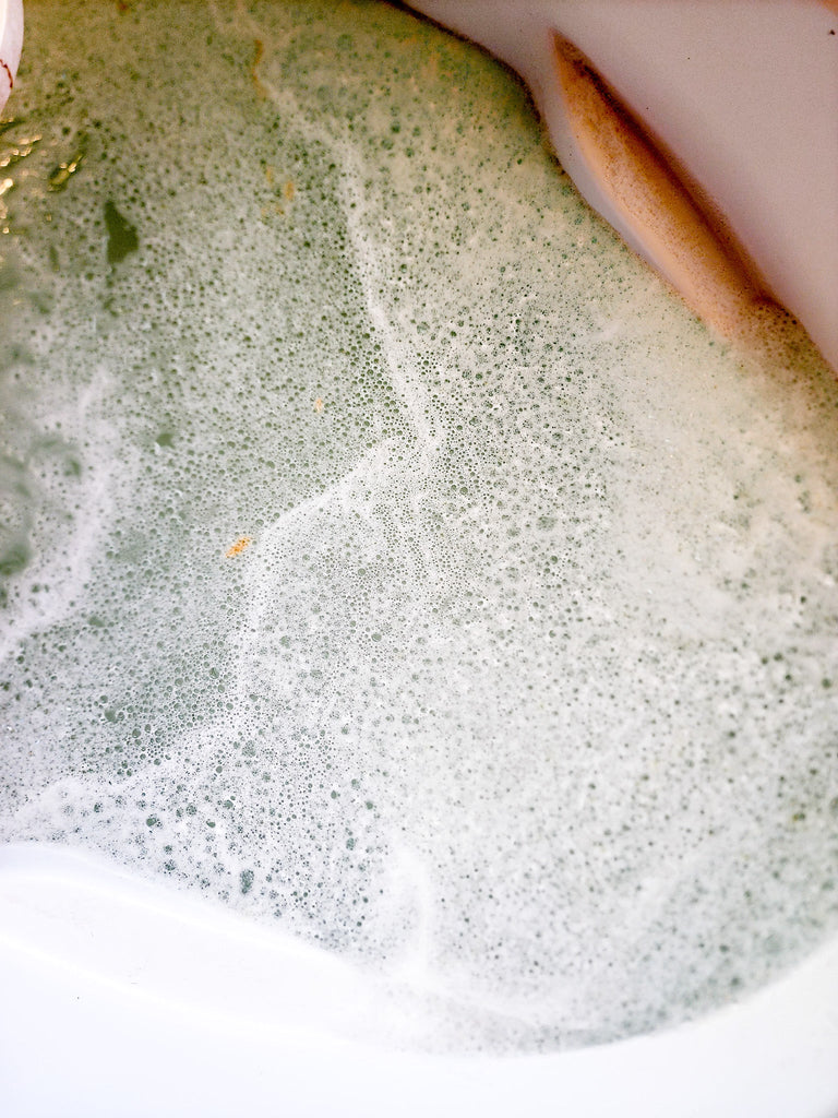 Yerba Mate Bath soak bubbles in white luxury bath tub.